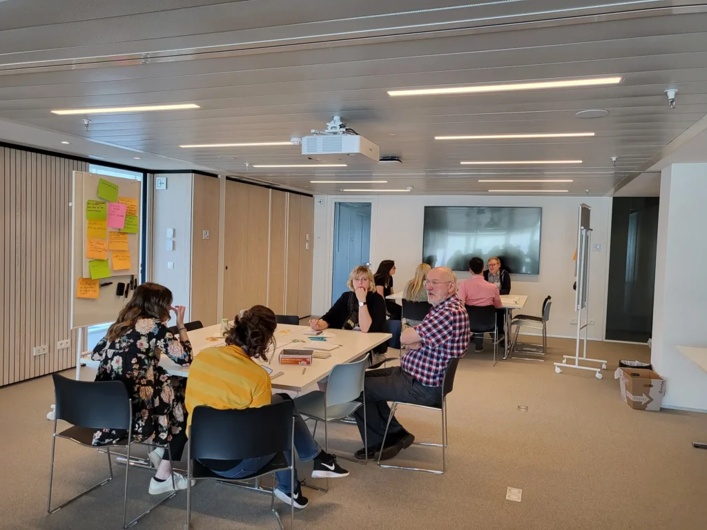 Two tables of 4 people in discussion in a large meeting room